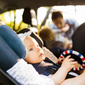 Little baby girl fastened with security belt in safety car seat